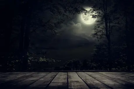 Dunkle Halloween-Kulisse mit Vollmond, Wolken und Bäumen hinter einer Holzterrasse für Oberbayloween.